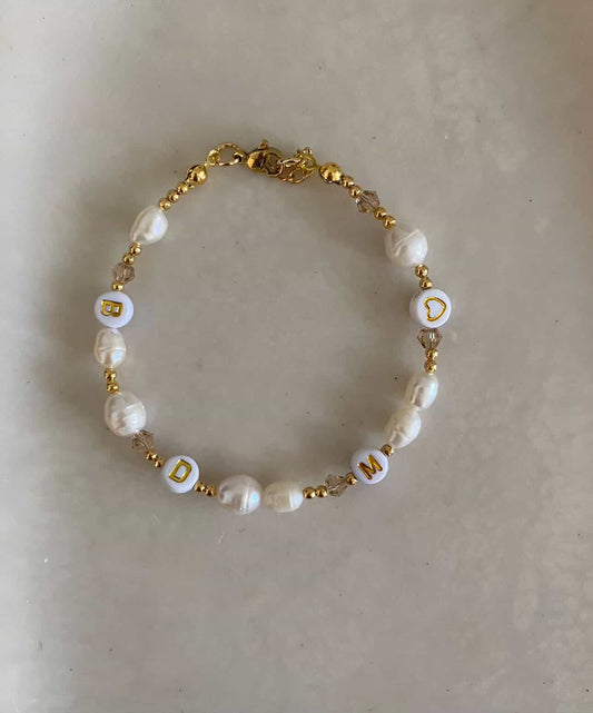 Gold bracelet featuring freshwater pearls and crystal beads with white and gold letter beads with the initials "BDM" and a heart