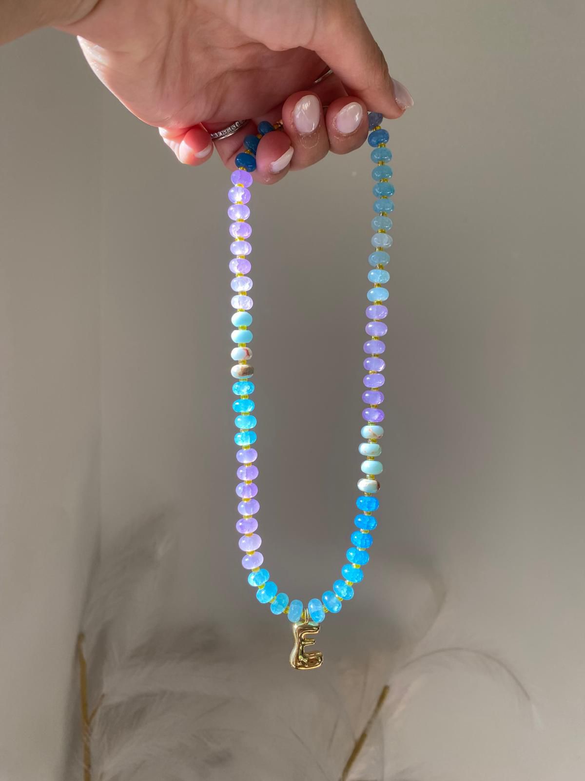 Bbeaded necklace featuring lilac, sky blue, aqua and turquoise gemstone rondelle beads with gold spacers and a gold balloon letter E initial charm pendant