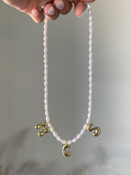 Necklace with stacked white freshwater pearls and three gold bubble initial charms spelling M, C, S