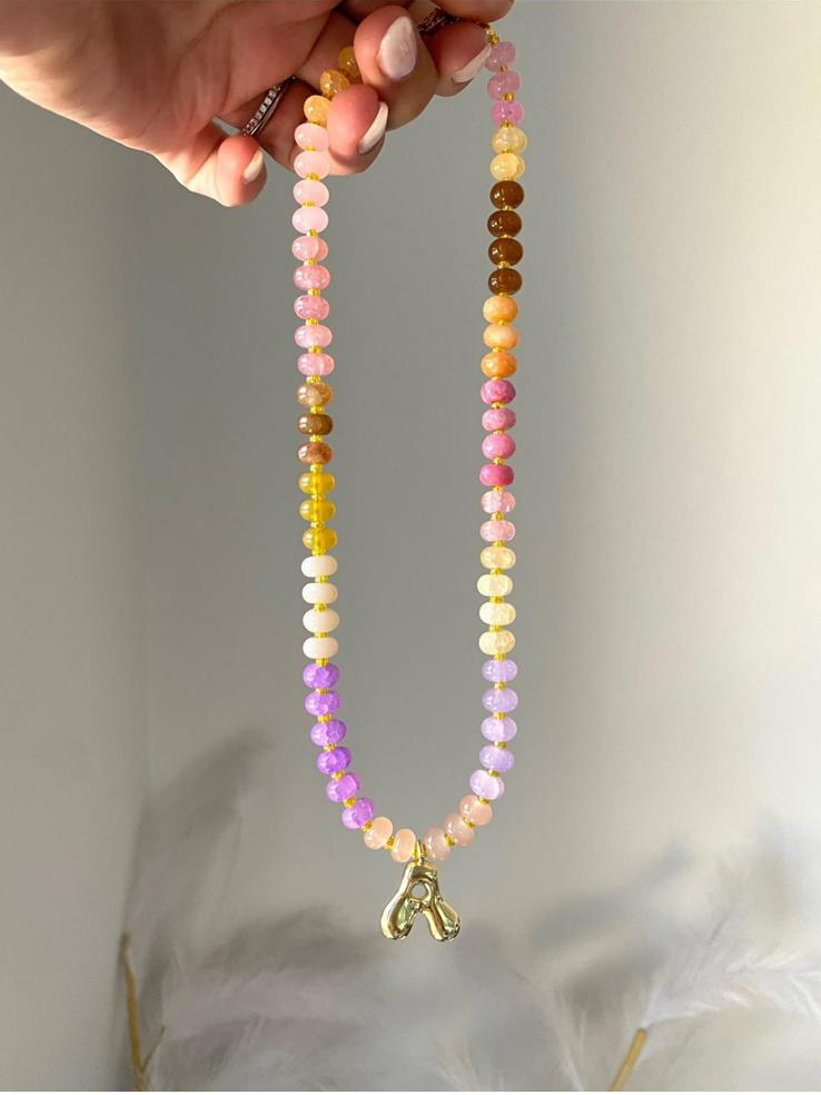 Beaded necklace featuring pink, yellow, orange, lilac and brown gemstone beads with gold spacers and a gold bubble letter R initial charm pendant