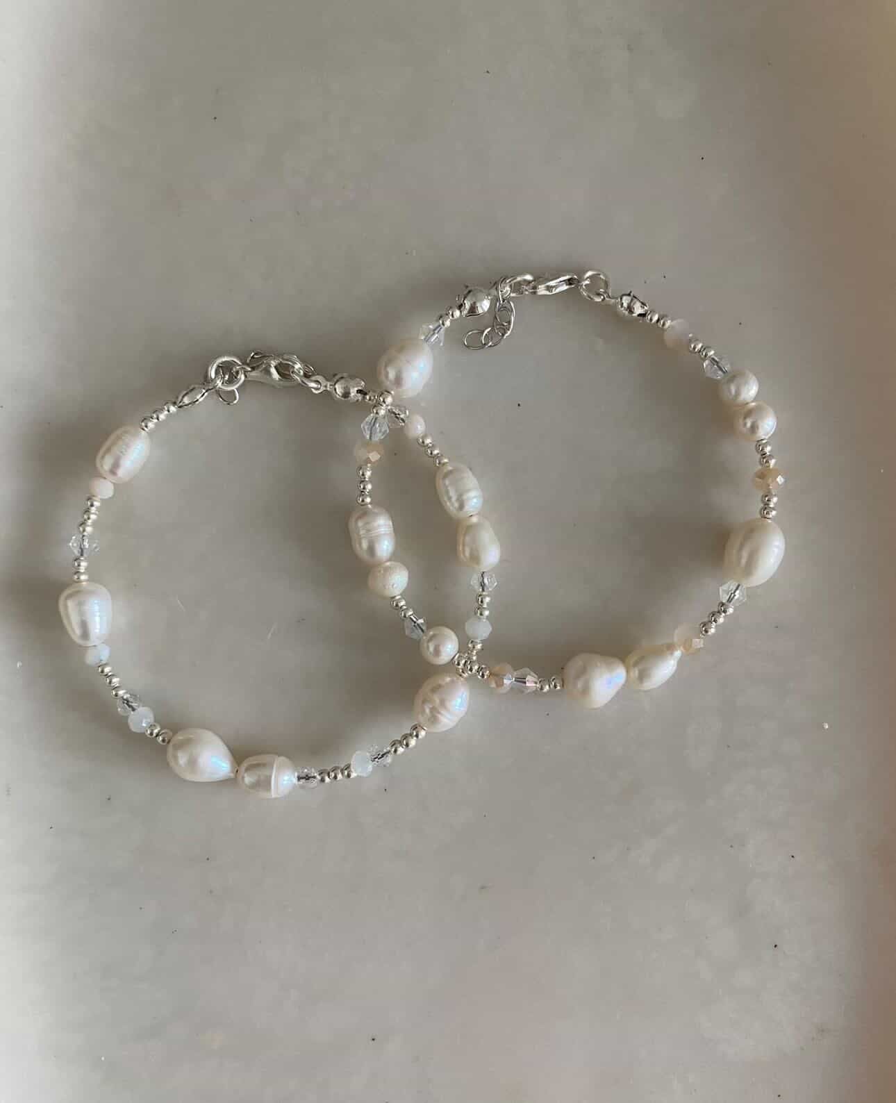Two delicate with freshwater pearl bracelets with crystal spacer beads and silver seed beads, displayed overlapping on a soft grey background