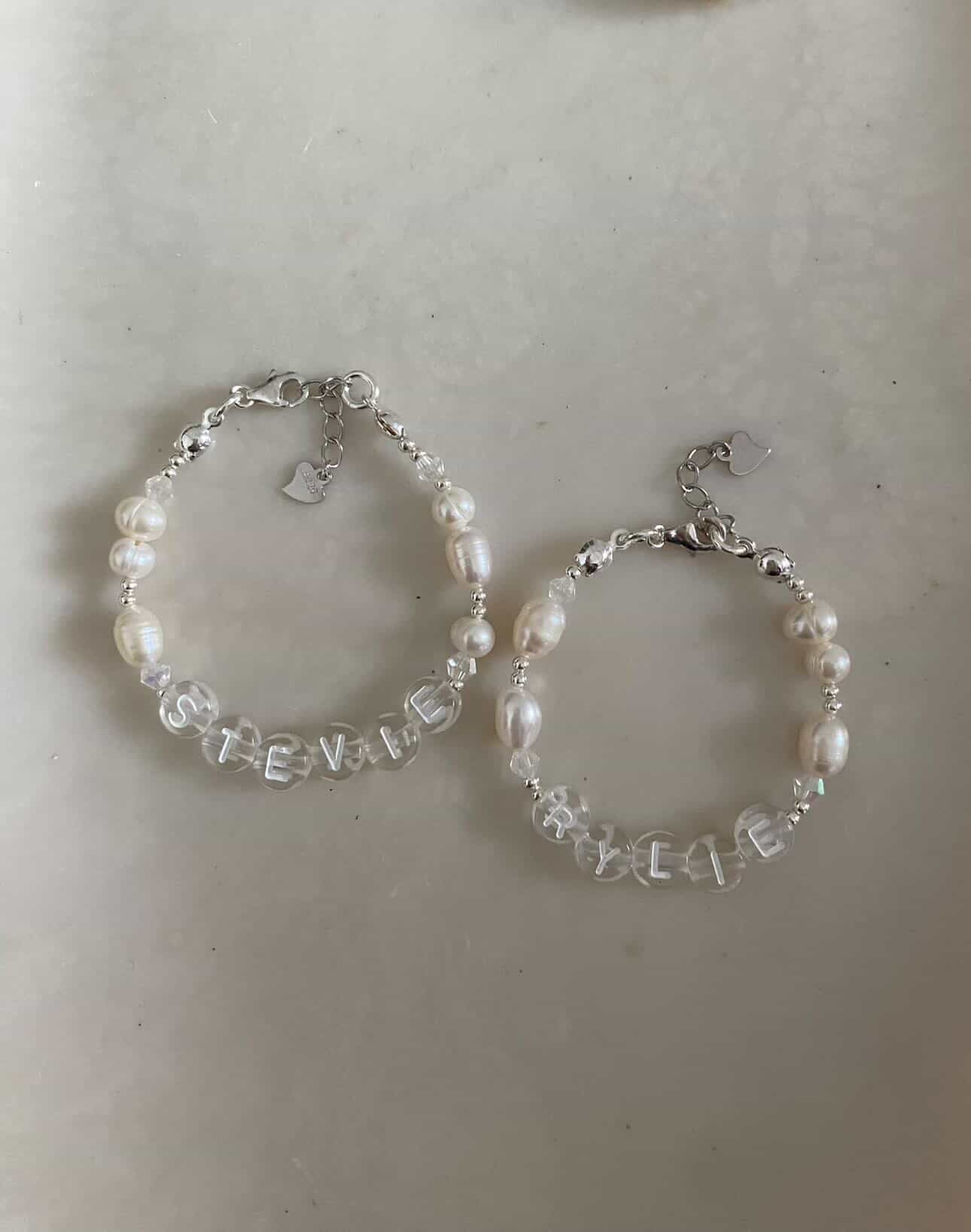 Two silver bracelets with pearls and customised with clear acrylic beads. The first spells Stevie and the second spells Rylie.