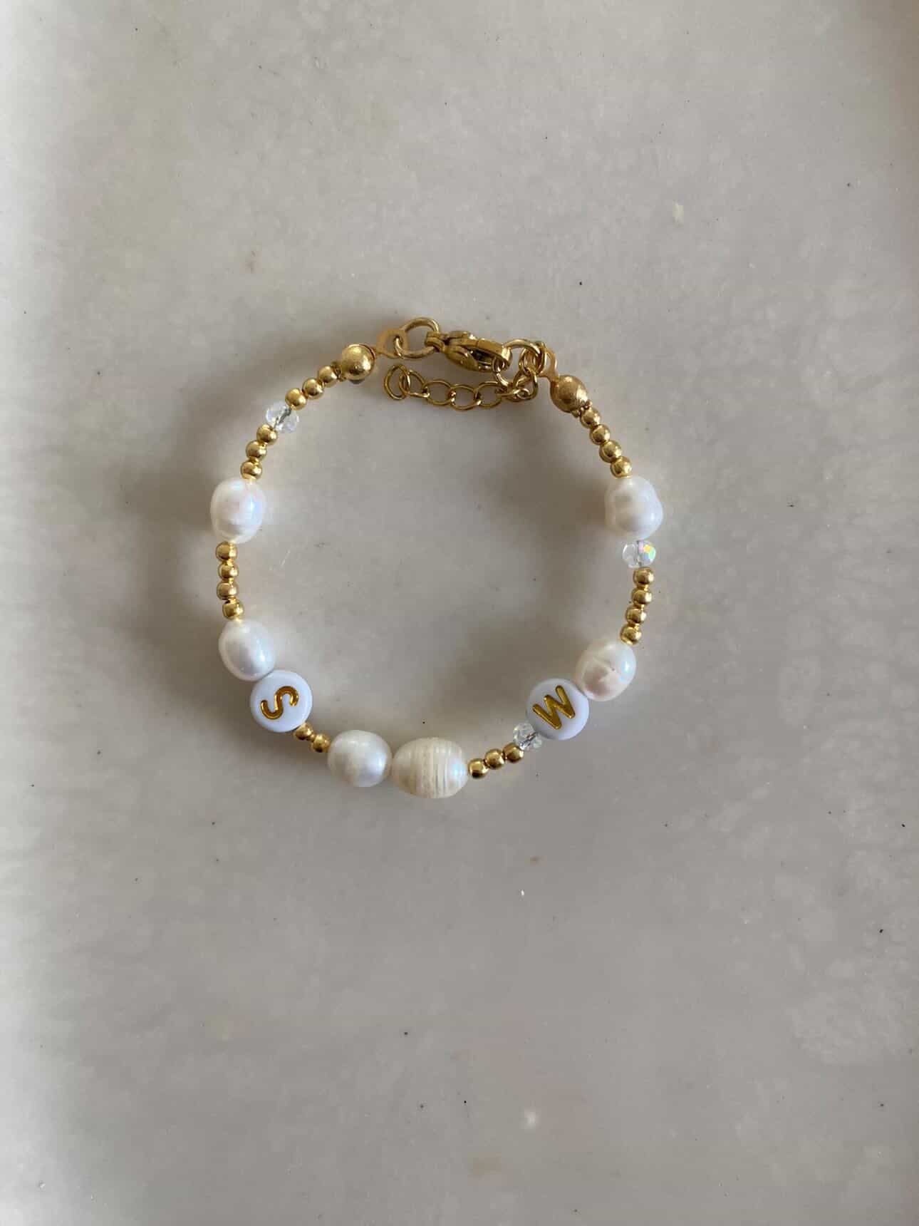 Gold bracelet with pearls, 2 white beads with S and W initials, lobster clasp.