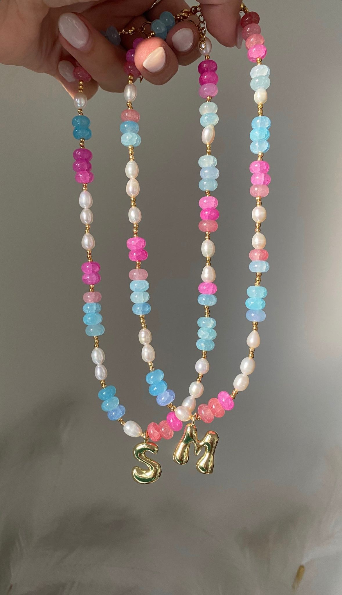 beaded necklace featuring bright pink and sky blue gemstone rondelle beads with freshwater pearl accents, gold ball spacers and a gold bubble letter initial charm pendant