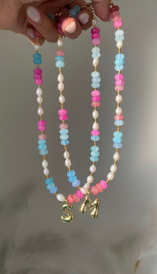 beaded necklace featuring bright pink and sky blue gemstone rondelle beads with freshwater pearl accents, gold ball spacers and a gold bubble letter initial charm pendant