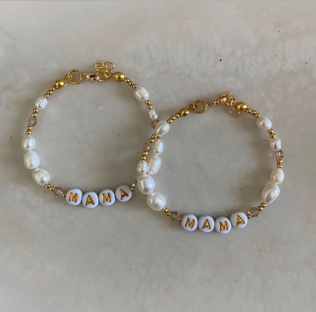 2 beaded bracelets of freshwater pearls, crystal beads and gold spacer beads, with white and gold letter beads spelling out "MAMA" 