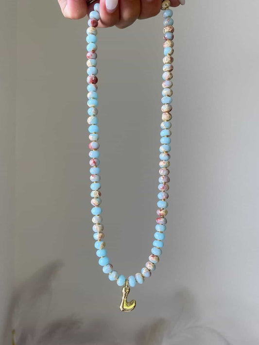 A turquoise and terracotta beaded necklace with gold spacers and a gold bubble letter L charm