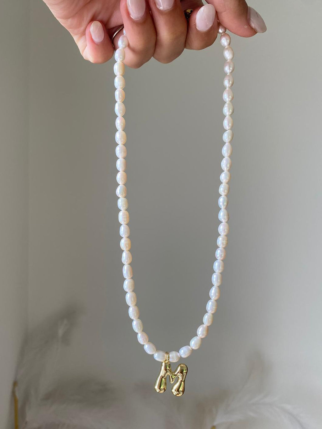 Pearl necklace with closely strung freshwater pearls and a gold bubble letter M initial pendant