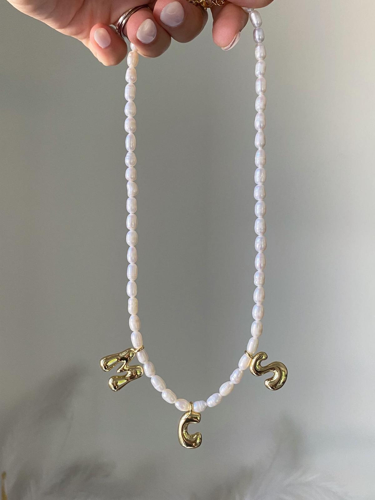 Necklace with stacked white freshwater pearls and three gold bubble initial charms spelling M, C, S