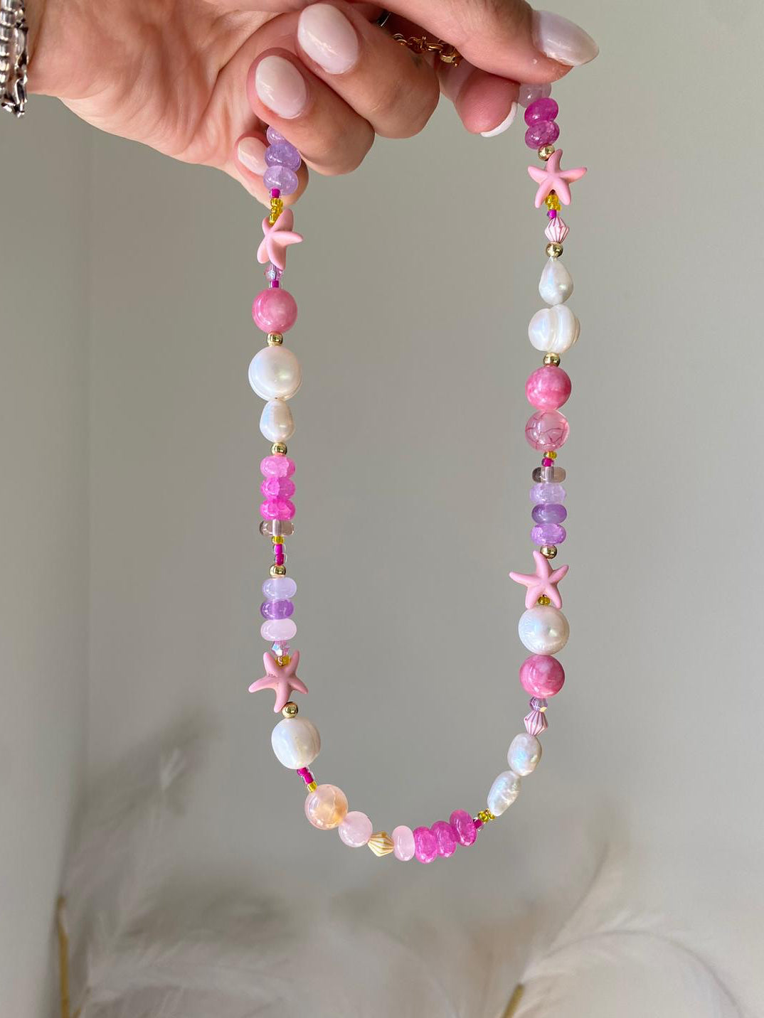 beaded necklace featuring freshwater pearls, hot pink and lilac gemstone beads, gold seed beads, and pink starfish charms